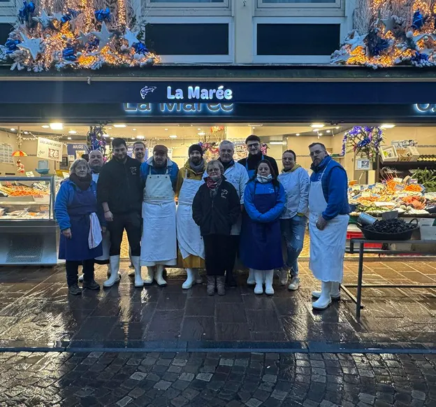 Groupe souriant de poissonniers devant leur étal de fruits de mer décoré à Saint-Germain-en-Laye dans les Yvelines 78