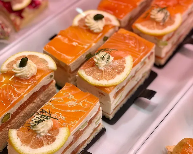Plusieurs tranches rectangulaires de saumon fumé et gâteau au fromage, garnies de citron et d'aneth à Saint-Germain-en-Laye dans les Yvelines 78