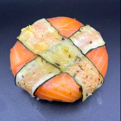 Plat de saumon rond, enveloppé de courgettes grillées, sur fond sombre à Saint-Germain-en-Laye dans les Yvelines 78